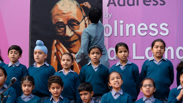 ダライ・ラマ法王のご講演に先立ち、法王を歓迎して生徒たちが歌を披露する中、法王の肖像画を描く画家のビラス・ナイク氏。2017年2月6日、インド、デリー（撮影：テンジン・チュンジョル / 法王庁））