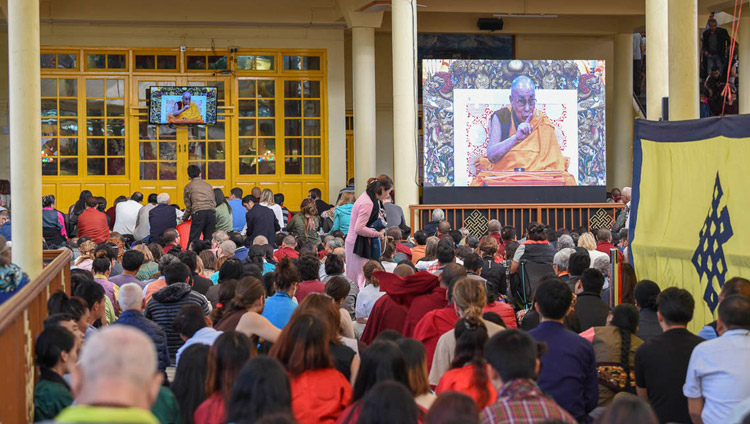 ツクラカンの中庭に置かれた巨大スクリーンでダライ・ラマ法王のお姿を拝見しながら説法を聞く参加者たち。2018年10月3日 インド、ヒマーチャル・プラデーシュ州ダラムサラ（撮影：テンジン・ペンデ / DIIR）