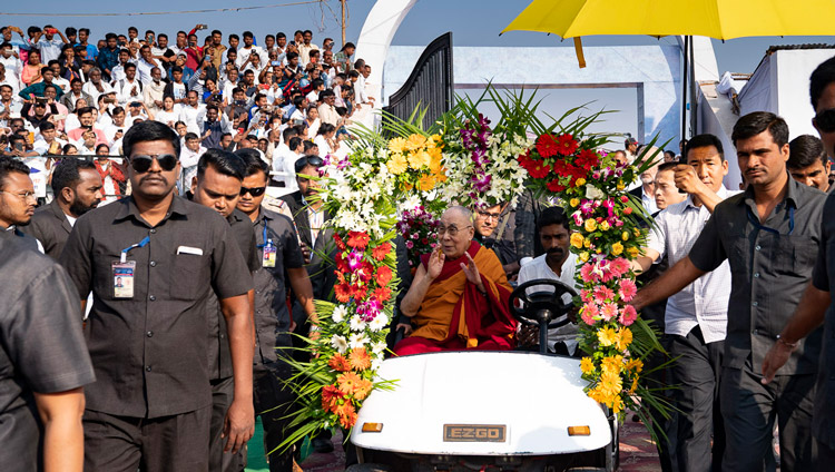 法話会の会場となったPES体育大学スポーツ・スタジアムのステージまで電気自動車に乗られ、集まった人々に手を振って挨拶をされるダライ・ラマ法王。2019年11月24日、インド、マハシュトラ州オーランガバード（撮影：テンジン・チュンジョル / 法王庁）