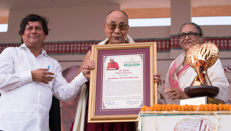 KISS大学から贈呈されたKISS人道支援賞の額を手にされるダライ・ラマ法王。2017年11月21日、インド、オリッサ州ブバネーシュワル（撮影：テンジン・チュンジョル / 法王庁）