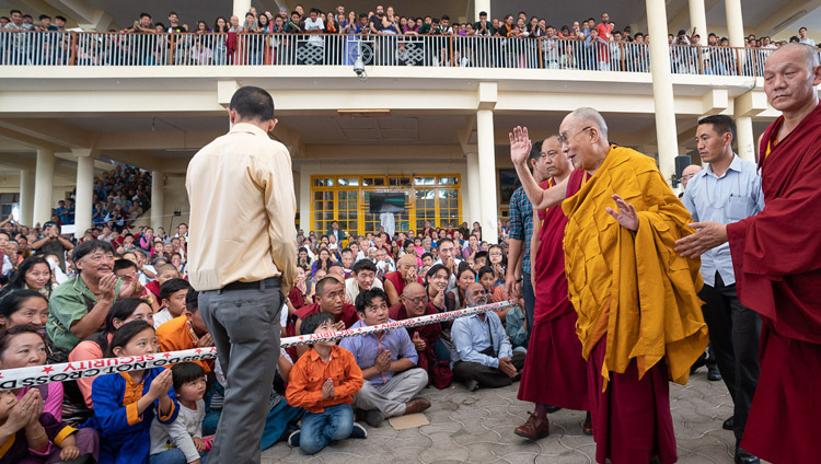チベット人の若者たちへの法話会が終了し、法王公邸へ戻られる途中で、ツクラカンの中庭に座った参加者たちに手を振って挨拶をされるダライ・ラマ法王。2018年6月8日、インド、ヒマーチャル・プラデーシュ州ダラムサラ（撮影：テンジン・チュンジョル / 法王庁）