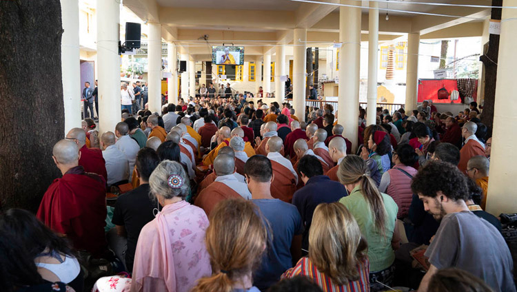 ツクラカン本堂の外に設置された大型モニターを見ながらダライ・ラマ法王の法話を視聴する人々。2018年10月4日インド、ヒマーチャル・プラデーシュ州ダラムサラ（撮影：テンジン・ジャンペル / 法王庁）