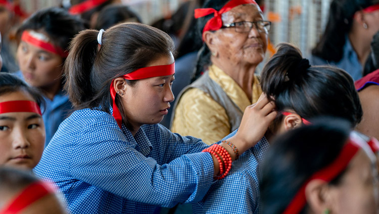 大悲世自在観音の灌頂授与の儀式の中で、赤い目隠しを額につけるチベット人の学生たち。2019年6月3日、インド、ヒマーチャル・プラデーシュ州ダラムサラ（撮影：テンジン・チュンジョル / 法王庁）