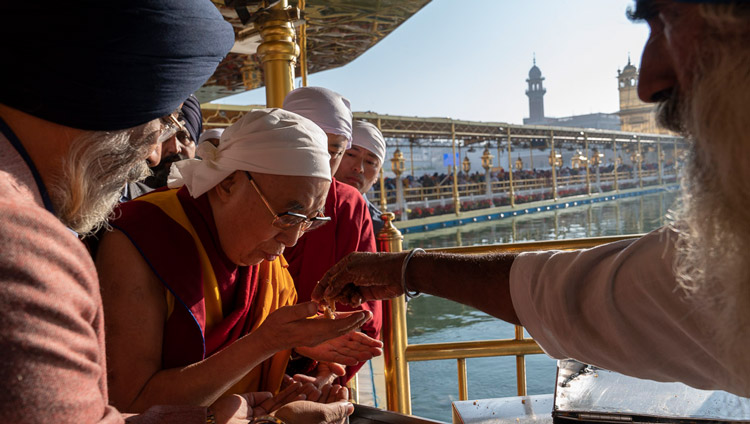 本殿を出られる前に、巡礼者に配られるプラサード（祝福を受けた食物）を召し上がるダライ・ラマ法王。2019年11月9日、インド、パンジャブ州アムリトサル（撮影：テンジン・チュンジュル / 法王庁）