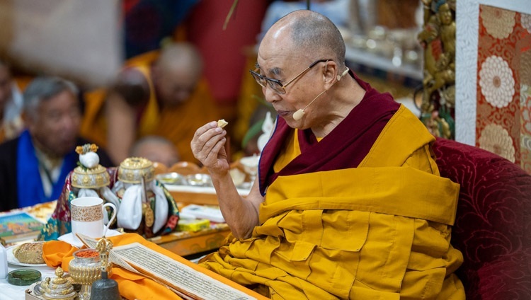 チベット人の若者たちへの法話会2日目、千手千眼観音菩薩の灌頂の前行中に短い休憩を取ってパンを召し上がるダライ・ラマ法王。2022年6月2日（撮影：テンジン・チュンジョル / 法王庁）